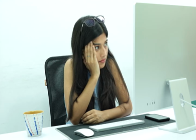 Shot of an Indian Girl having headache while working on a Computer in office