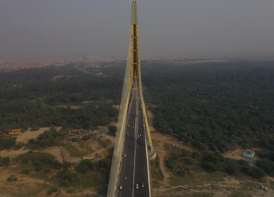 An aerial shot of the Signature Bridge with adjoining roads with cars moving in New Delhi, India